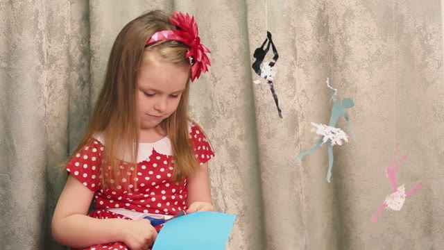 Girl Cuts A Blue Image. Near Weighs Paper Ballerina.