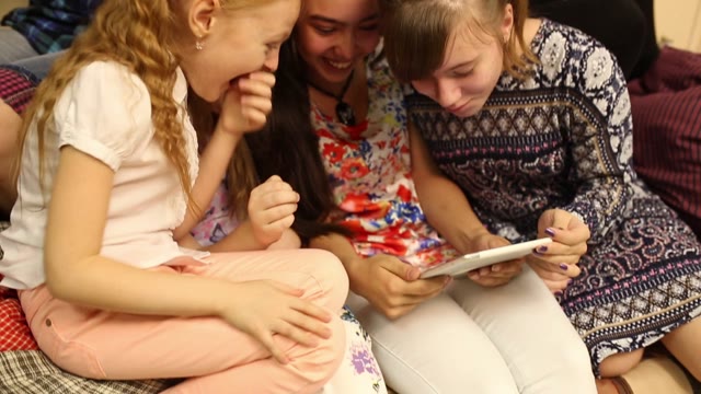 Children Play With The Tablet. On The Wall Of Children's Drawings.