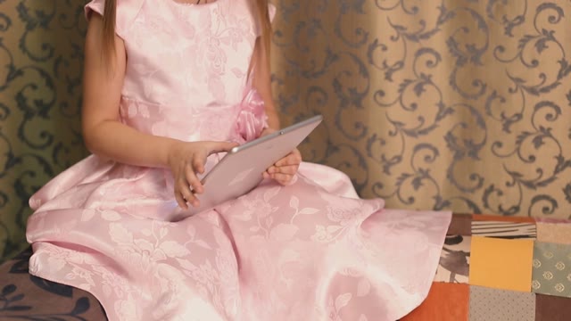 Serious Baby Girl Holding A Tablet.