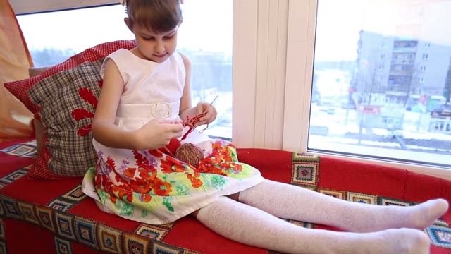 Cute Little Girl Sitting By The Window And Making Crafts.