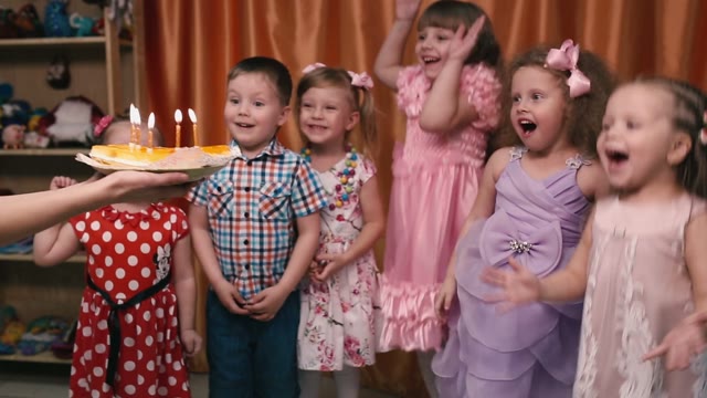 Young Children Blow Out The Candles On The Cake And Happy.