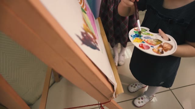Two Little Girls Draw Paints On Canvas.