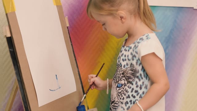 Little Girl Draws A Blue Paint On Paper.