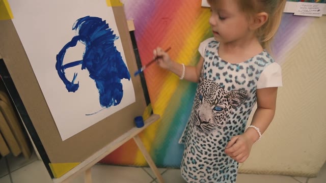 Little Girl Draws A Blue Paint On Paper.