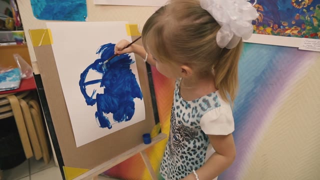 Little Girl Draws A Blue Paint On Paper.