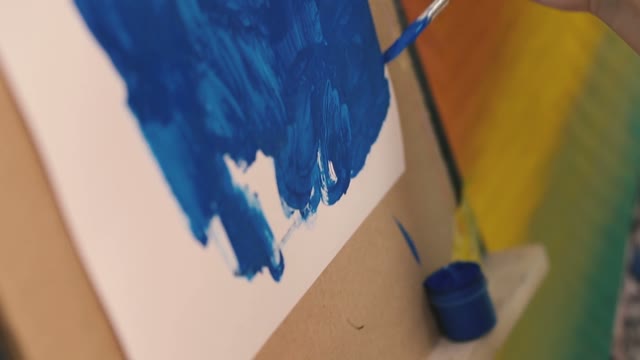 Girl Draws Blue Paint On Paper.