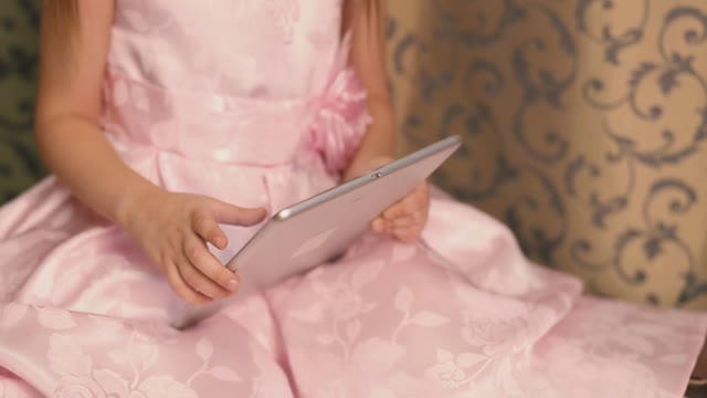 The Girl Smiles And Leads The Finger On The Tablet.
