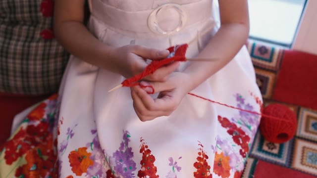 Girl Doing Crafts Of Red Yarn And Wooden Sticks.