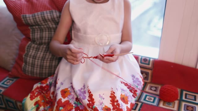 The Little Girl With Enthusiasm Red Yarn Unwinds With Sticks.