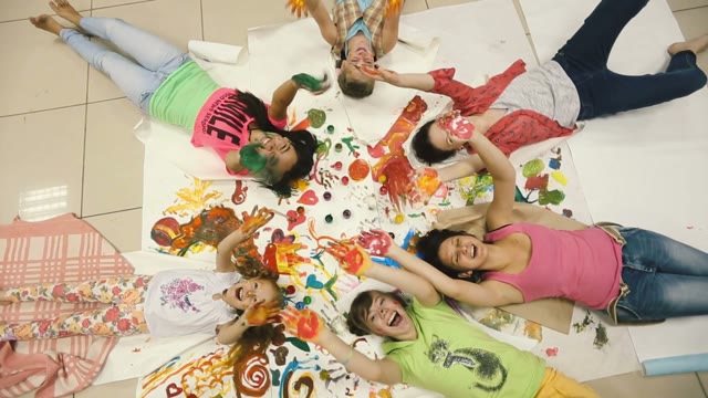 Little Girl With Colored Hands Lie On The Floor In A Circle.