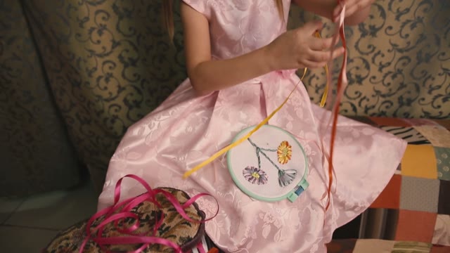 Cute Little Girl In A Pink Dress Untangles Colored Ribbons.