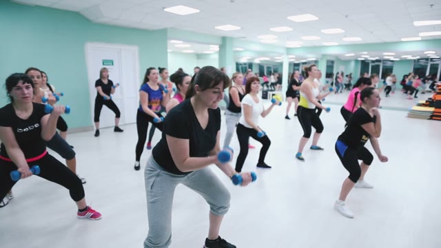 Girls At The Gym Exercising With Dumbbells.
