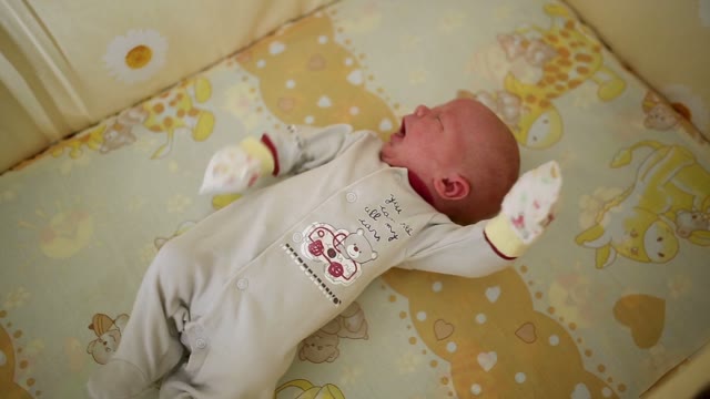 Newborn Waving His Arms And Yawns During Sleep. Close-up.
