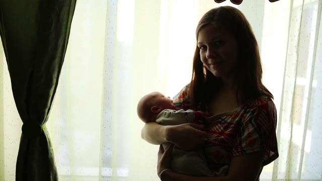 Happy Mother Holding A Baby In Her Arms, Kissing Him.