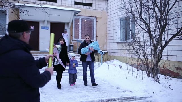 Happy Family Coming Out Of The Hospital With The Newborn. Slow Motion