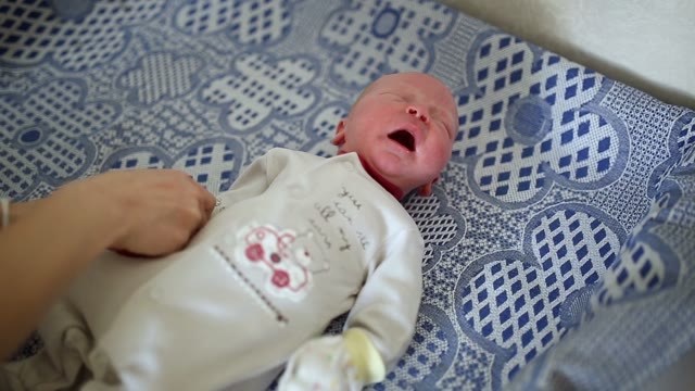 Mom Puts The Baby Mitten, He Cries. Close-up.