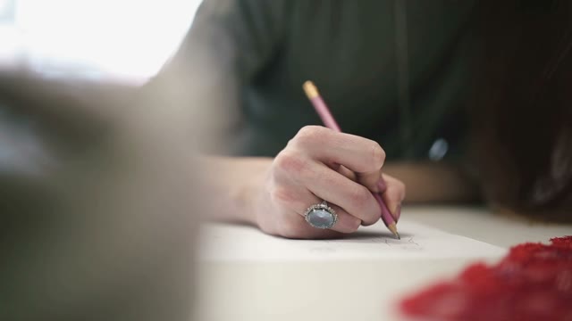 The Girl Draws A Sketch On Paper. Close-up.