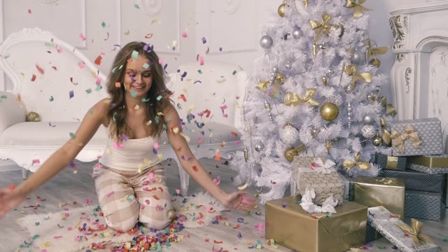 Beautiful Girl Throws Up Confetti Near The Christmas Tree In Slow Motion
