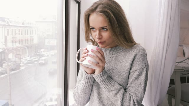Young Girl Warms The Fingers And Drinking From A Glass