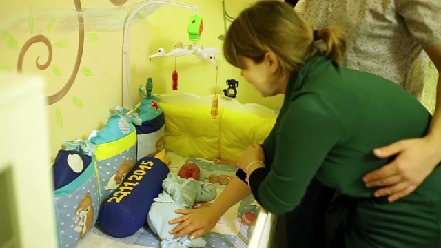 Happy Parents Stroked The Baby In The Crib