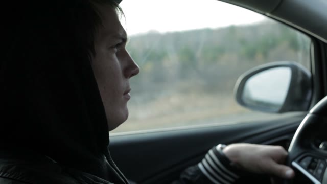 Serious Young Man Is Driving A Car. Close-up