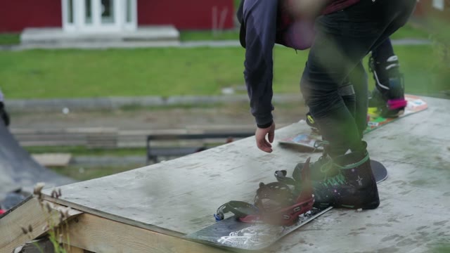 Young Man Buttoning Fastening On A Snowboard