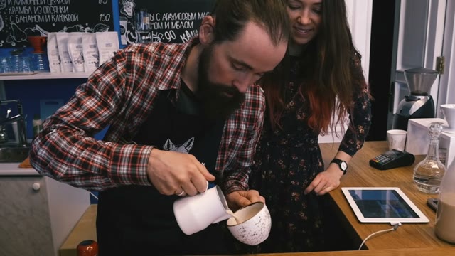 She Watches As The Barista Adds The Milk In Coffee. Slow Motion. Close-up