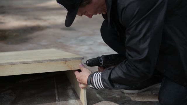 Man Twists The Screws On The Wooden Structure In The Skatepark