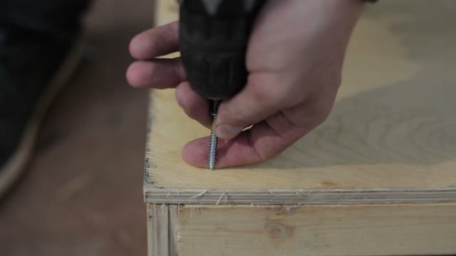 Carpenter Twists Screws On A Wooden Structure For The Skatepark