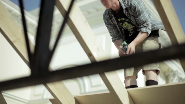 Man Drills A Wooden Structure