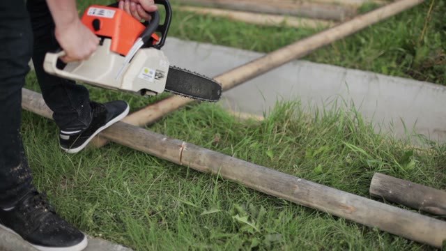 Carpenter Sawing A Log In Half A Chainsaw