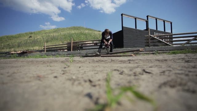 Man Works Chainsaw Against The Backdrop Of The Hill