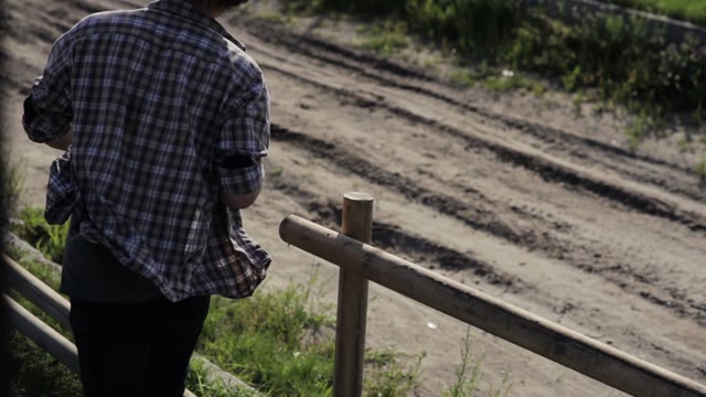 Man Builds A Fence Made Of Logs Using A Power Screwdriver