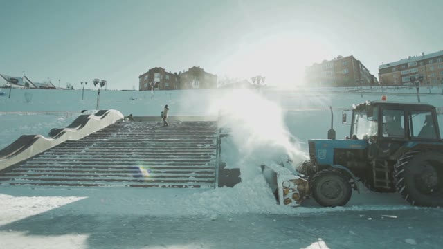 Tractor Cleans Snow. A Snowboarder Performs A Trick