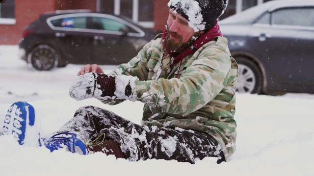 Man Takes Off His Gloves Sitting On Snow