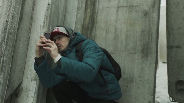 Man On A Smartphone Photographs And Explains Among Concrete Slabs
