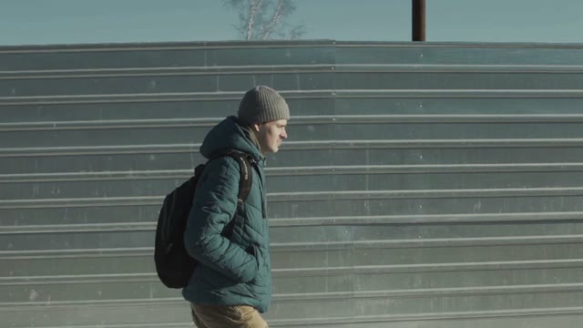 Man Goes Along The Metal Fence