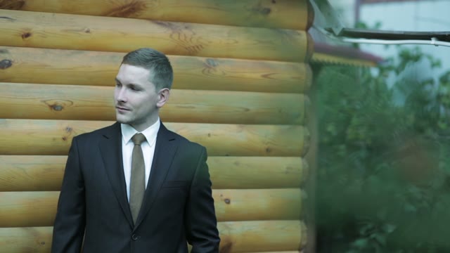 Man In A Suit Standing Near The Wooden Wall