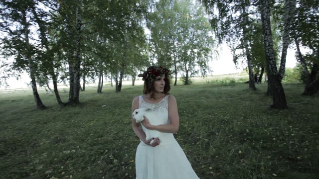 Bride Holding A Rabbit In Her Arms In The Forest