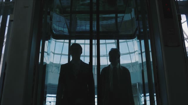Two Men Emerge From The Glass Elevator
