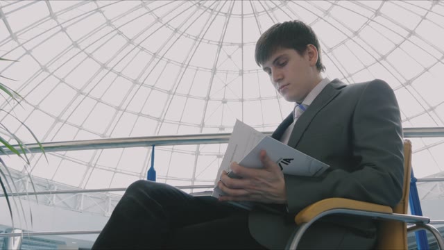 Businessman Sitting In A Chair With Magazine