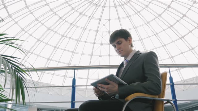 Businessman Sitting In A Chair With A Tablet