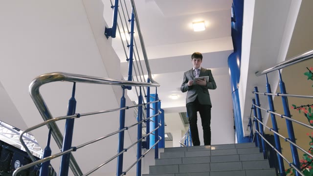 Businessman Walking Down The Stairs With A Tablet In Hands