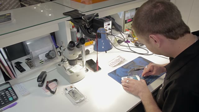 Man Repairing A Broken Phone In The Department Of Warranty