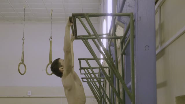 Young Man Is Engaged On The Bar In The Sports Class