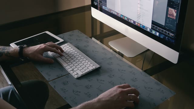 Young Man Works On The Computer And A Tablet