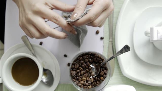 The Girl In The Cafe Makes A Bag With A Coffee Beans