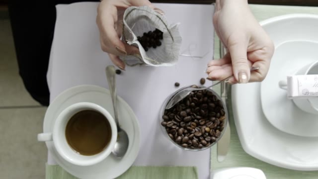 The Girl In The Cafe Makes A Bag With A Coffee Beans