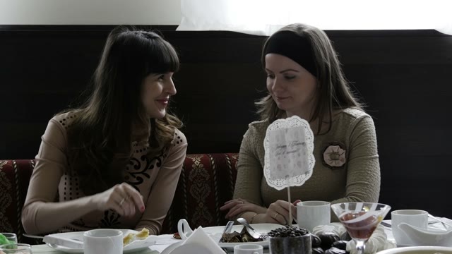 Two Women Gossiping At A Table In The Cafeteria