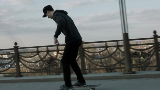Guy Rides A Skateboard On The Sidewalk Of The Road Bridge